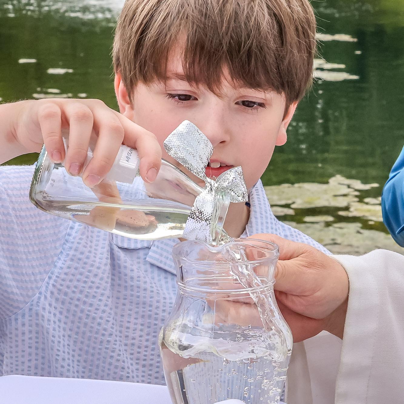 Ferdinand füllt das Wasser, das er morgens aus der Schwalm geschöpft hat, in den Krug. Damit wird der Achtjährige getauft.